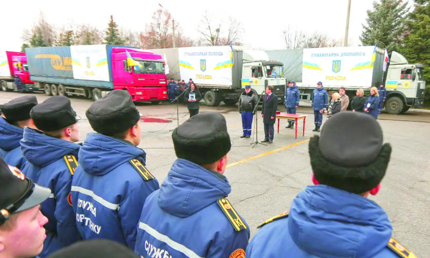 عسكريون يقفون أمام شاحنات محملة بالمساعدات الإنسانية مخصصة لسكان الشرق الأوكراني في مدينة خاركيف أمس (إ.ب.أ)