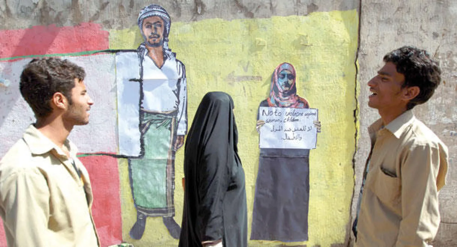 يمنيون ينظرون إلى صورة {غرافيتي} تحمل كتابات مناهضة للعنف على احد الجدران في العاصمة اليمنية صنعاء أمس (أ.ف.ب)