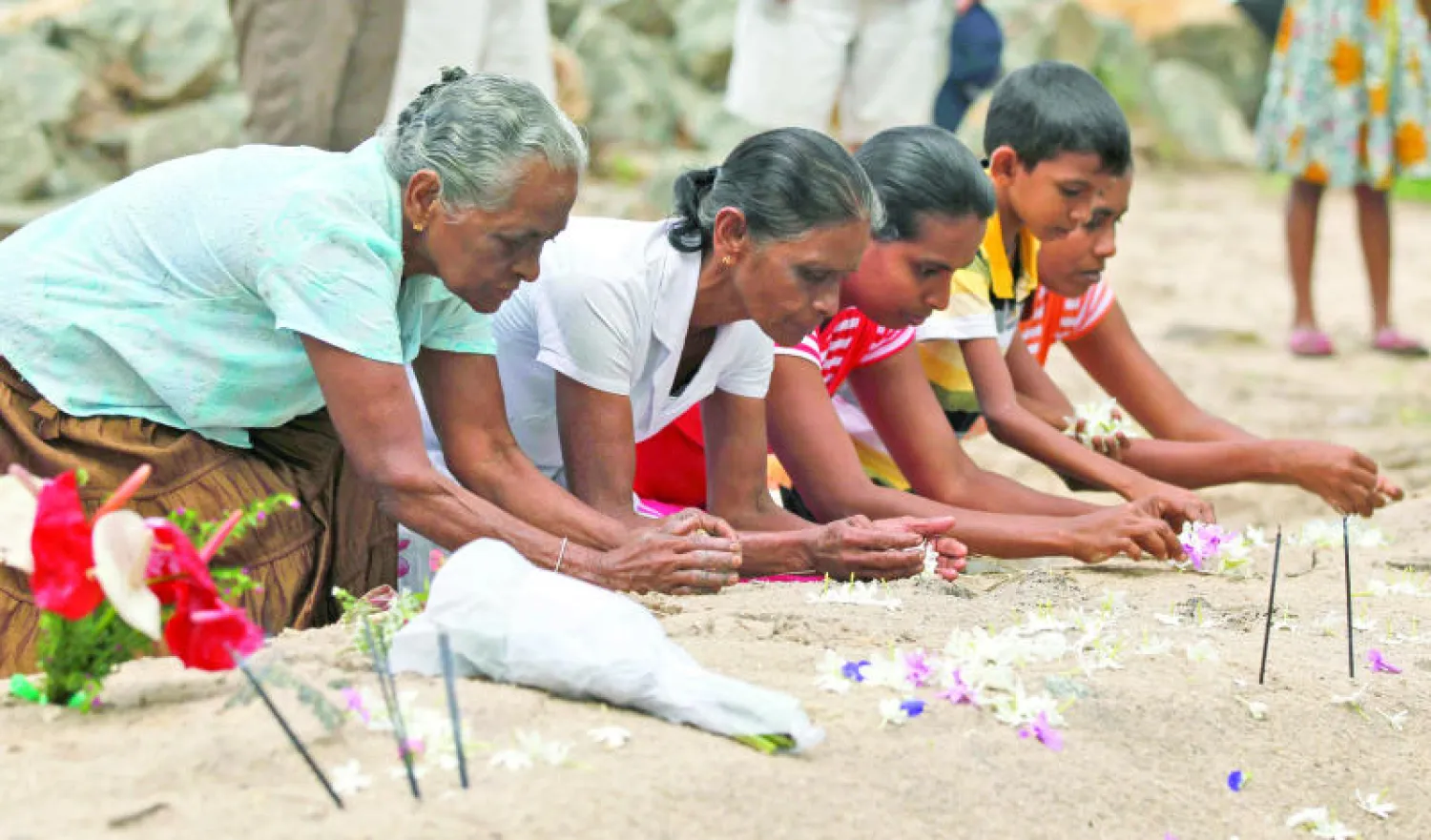 سكان يتذكرون أقارب لهم لقوا حتفهم في تسونامي 2004 أمام مقابرهم في منطقة بيراليا بسريلانكا أمس (أ.ب)