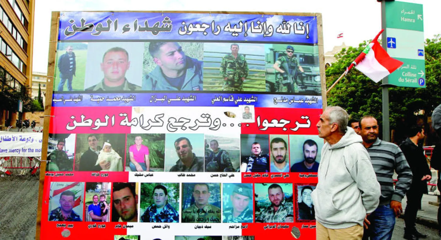 أقرباء الجنود المختطفين عند «داعش» يقفون بالقرب من ملصق للحملة من أجل إطلاق سراحهم أمام قصر الحكومة (إ.ب.أ)