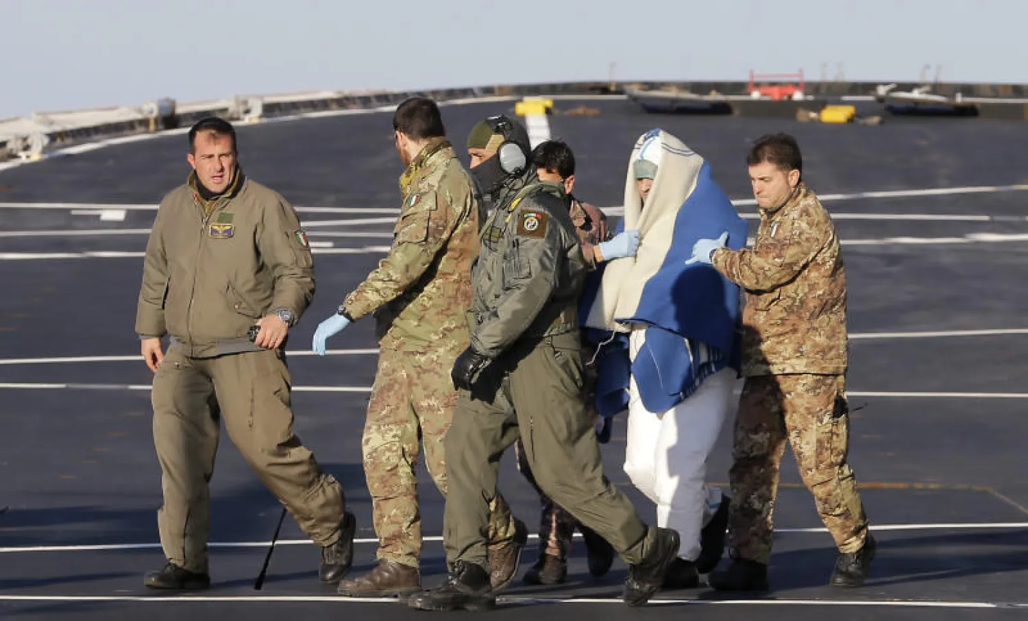 عناصر من البحرية الإيطالية يساعدون رجلا جرى إنقاذه من العبّارة العالقة على متن سفينة إيطالية في البحر الأدرياتيكي أمس (أ.ب)