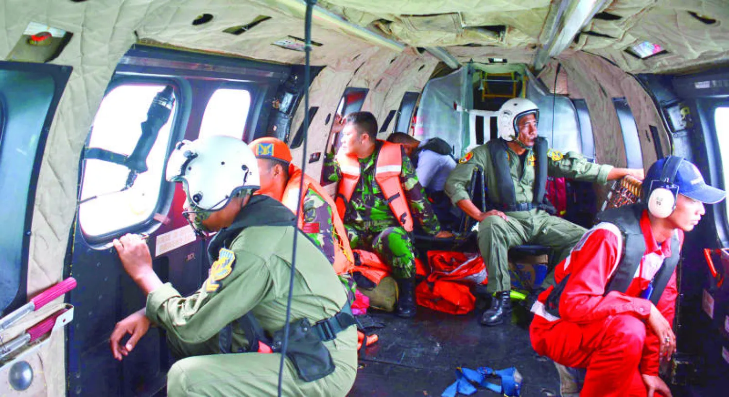 ضباط ينظرون من نوافذ طائرة هليكوبتر تابعة للقوات المسلحة الإندونيسية بحثا عن ضحايا أو حطام للطائرة المفقودة في بحر جاوا أمس (أ.ب)