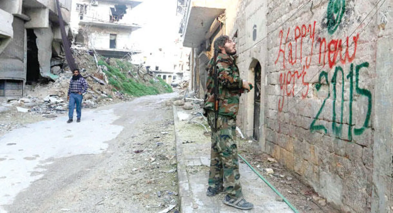 عنصر من الجيش السوري الحر قرب مدينة حلب يكتب عبارة بالإنجليزية للتهنئة بالعام الجديد (رويترز)