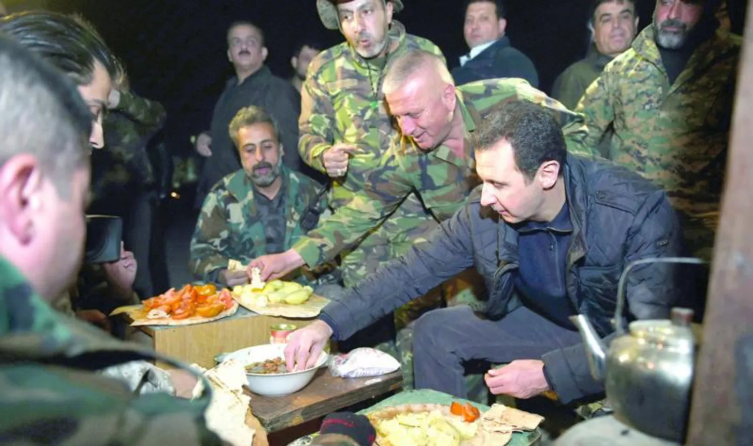 صورة نشرتها وكالة سانا الرسمية عن زيارة الأسد لقواته قرب جوبر يتناول معهم الطعام (أ.ف.ب)