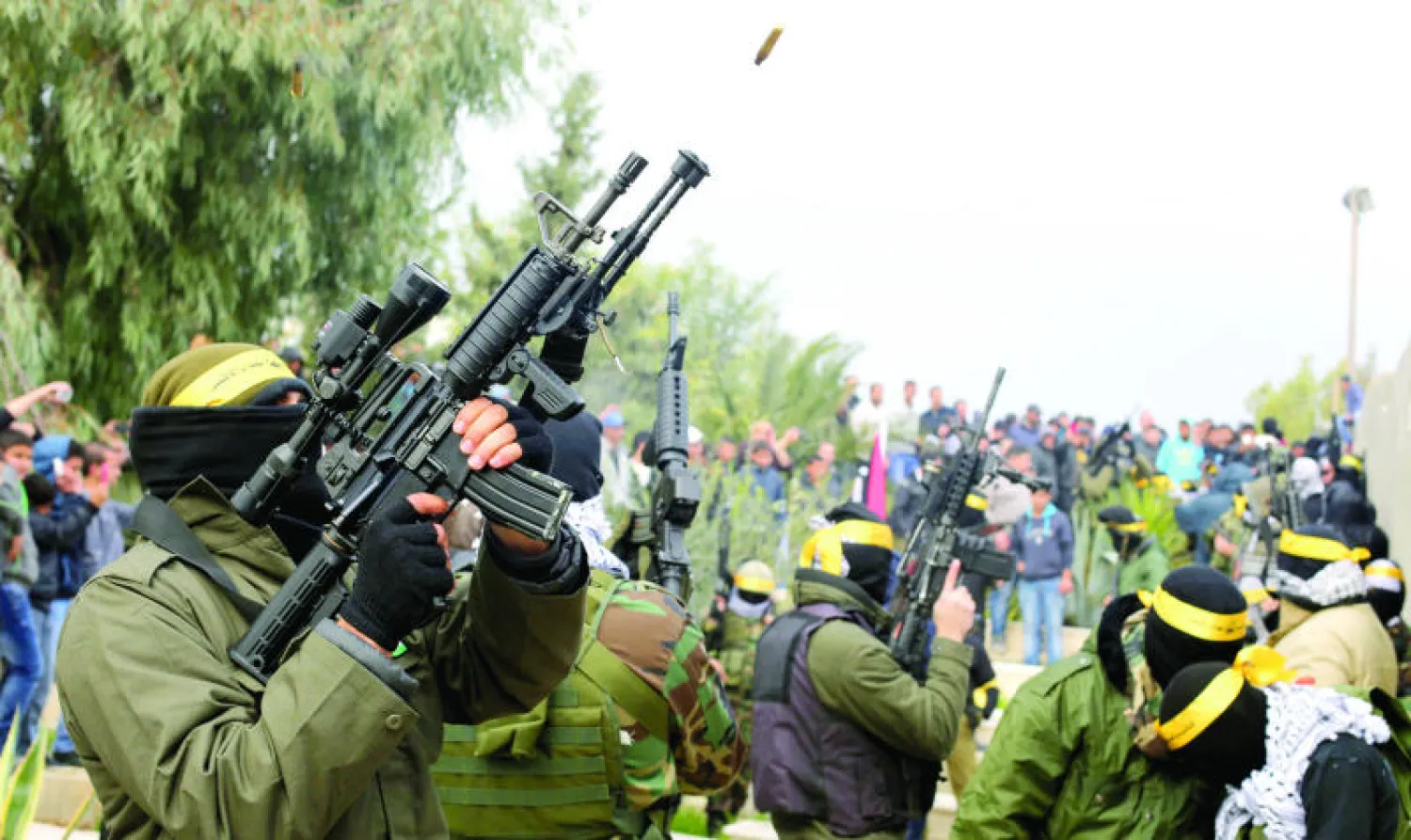 مسلحون من «كتائب شهداء الأقصى» الجناح العسكري لفتح يطلقون النار في احتفال بالذكرى الـ50 لفتح في مخيم قلنديا (أ.ف.ب)