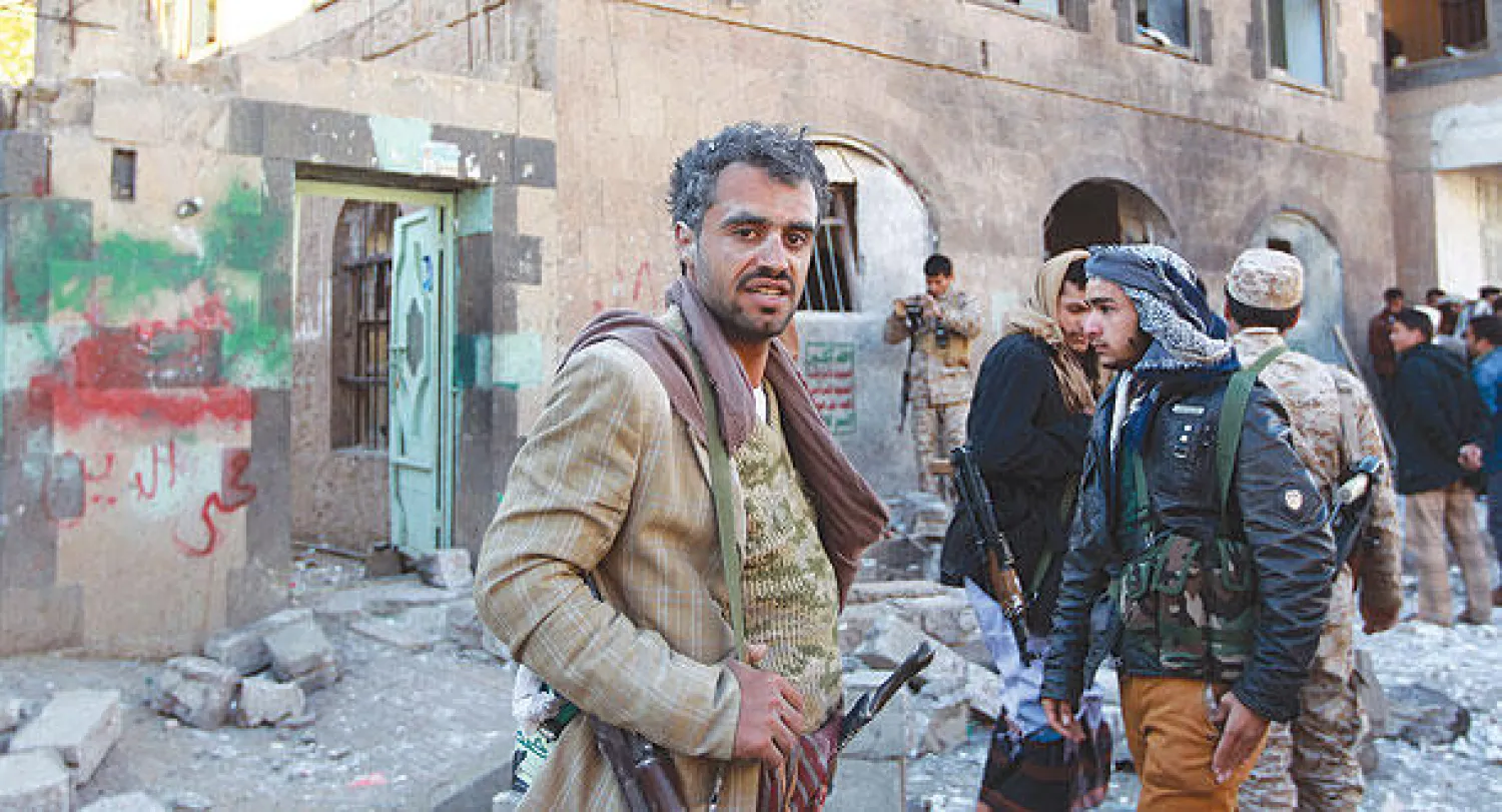 افراد من مليشيا الحوثيين يتجمعون خارج مبنى يستخدم مقرا أمنيا لهم  بعدما استهدف بقنبلة في صنعاء أمس (ا.ف.ب)