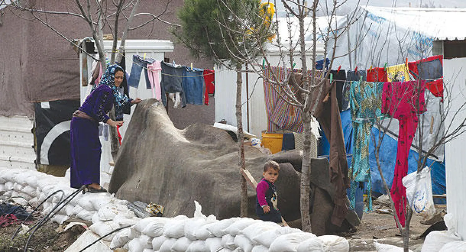 لاجئة سورية تحاول تحصين خيمتها في البقاع اللبناني أمس من فيضانات وثلوج (أ.ب)