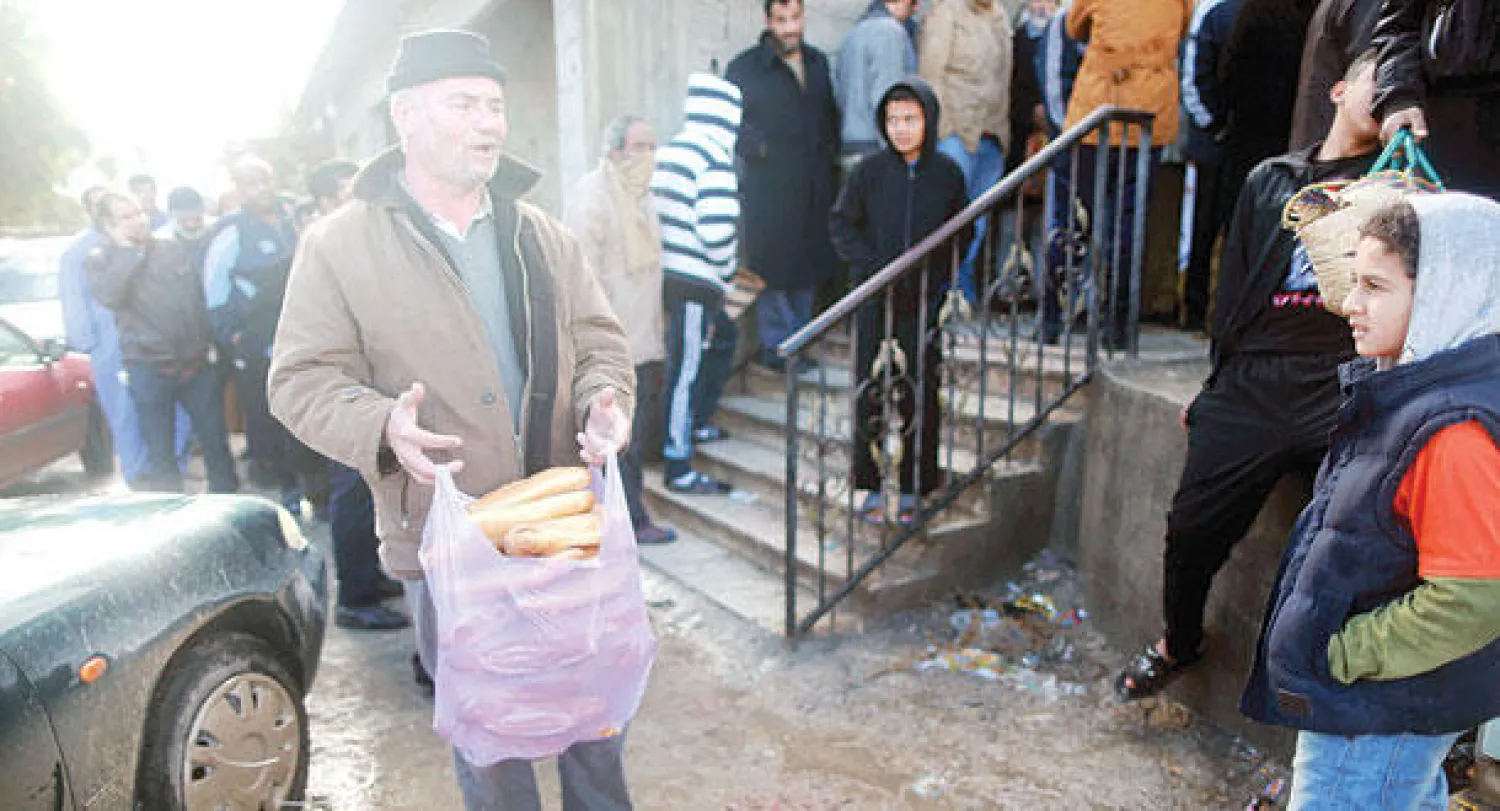 ليبي حصل على بعض الخبز في طابور طويل ببنغازي حيث يعاني السكان من وضع صعب بسبب الاشتباكات بين الفصائل (رويترز)