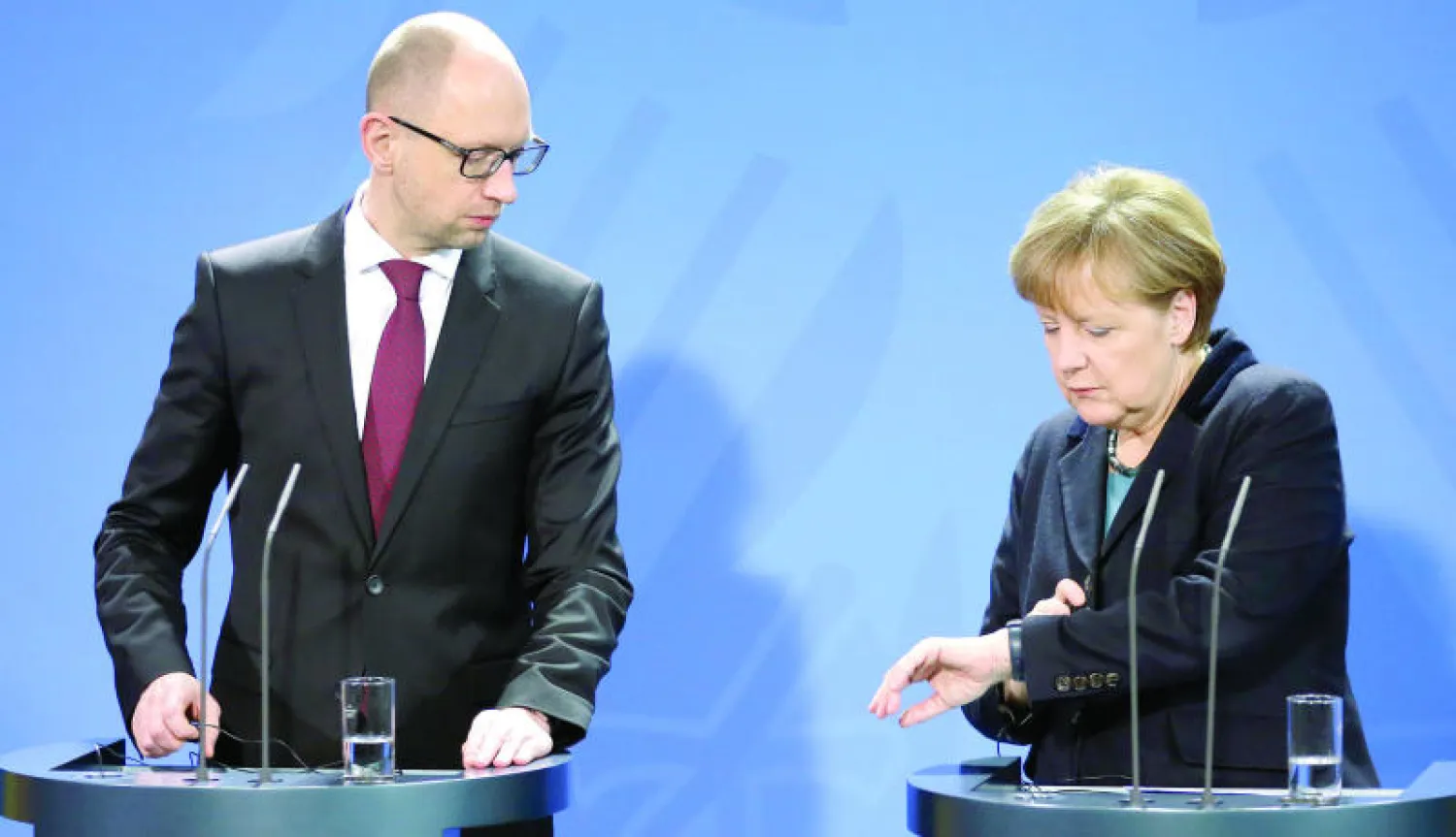 ميركل تنظر إلى ساعتها أثناء مؤتمرها الصحافي المشترك مع رئيس الوزراء الأوكراني في برلين أمس (أ.ب)