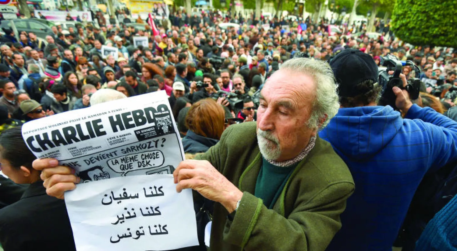 تونسي يعرض نسخة من مجلة «شارلي إيبدو» أثناء احتجاجات تضامنية في العاصمة تونس مع الصحافيين التونسيين اللذين أعلن إرهابيون في ليبيا إعدامهما أول من أمس (أ.ف.ب)