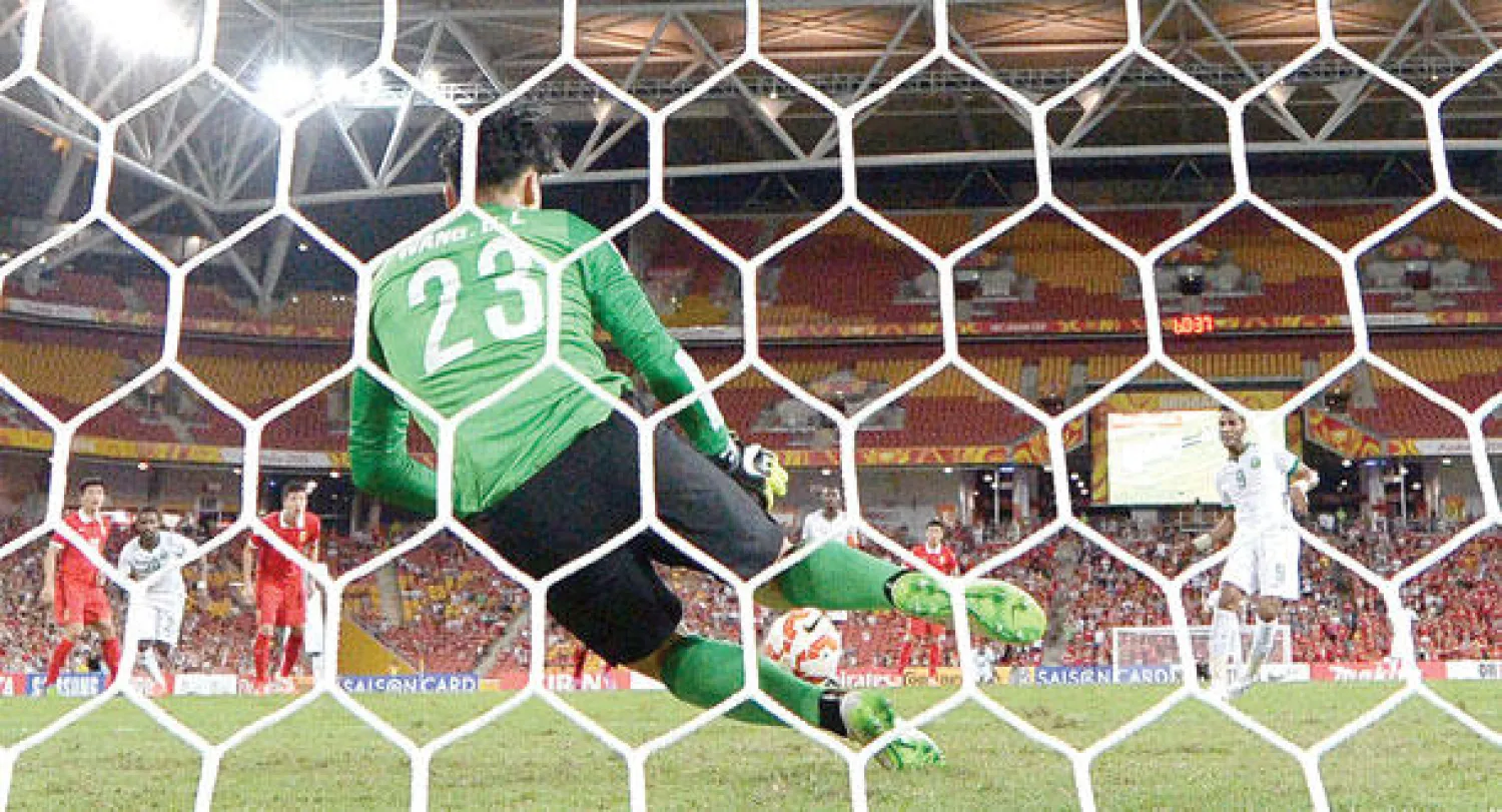 حارس الصين يتصدى لركلة الجزاء التي نفذها مهاجم المنتخب السعودي نايف هزازي (أ.ف.ب)