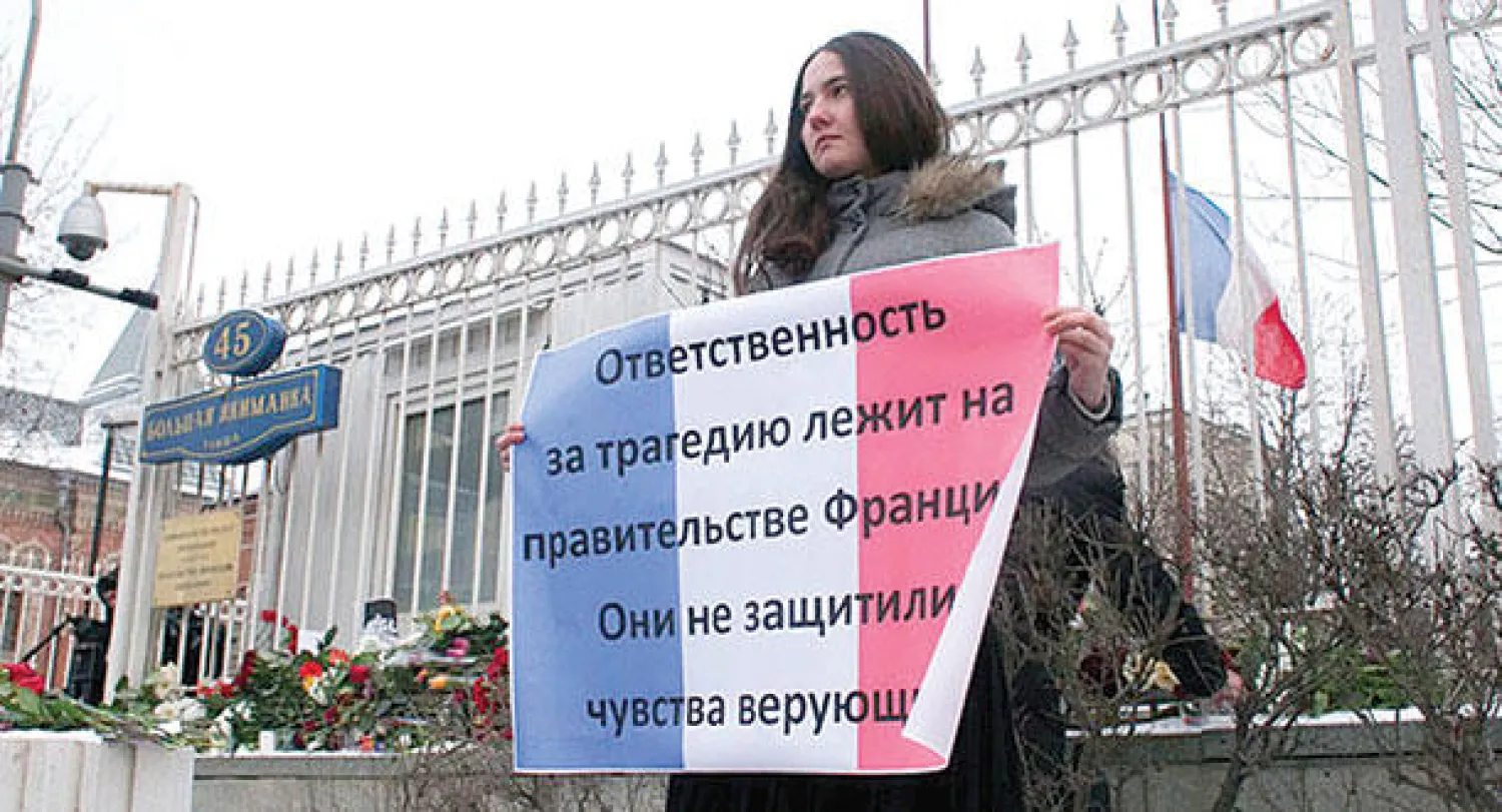 ناشطة روسية تحمل لافتة أمام السفارة الفرنسية في العاصمة باريس أول من أمس.. تقول فيها: «الحكومة الفرنسية تتحمل مسؤولية الكارثة» («الشرق الأوسط»)