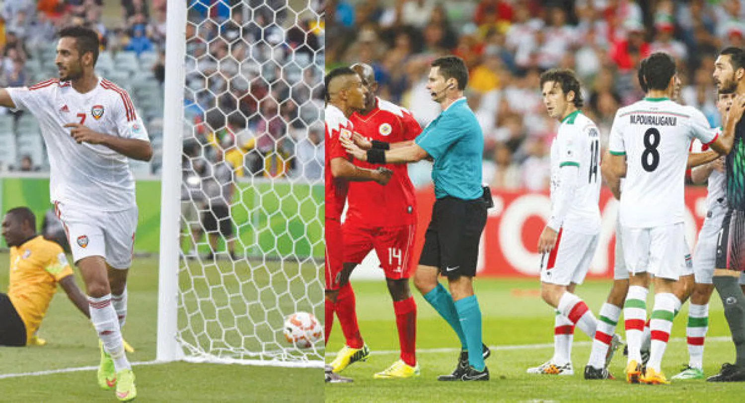 حكم المباراة يحول دون احتكاك البحريني فوزي عايش وحارس إيران علي رضا ببعضهما بعضا خلال المواجهة (رويترز)  -  الإماراتي علي مبخوت يحتفل بهدفه في مرمى قطر (أ.ف.ب)