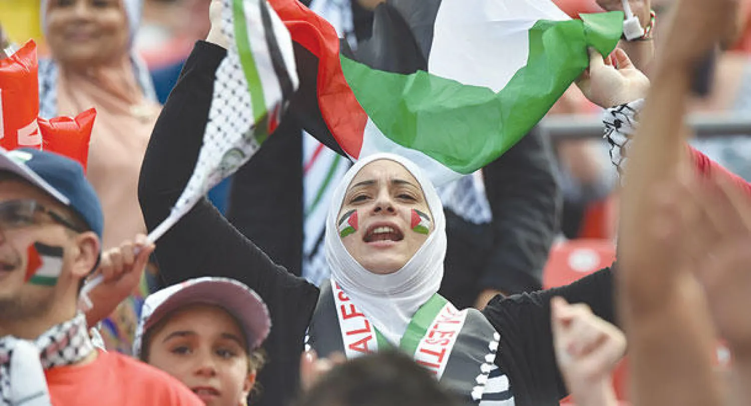 مشجعة فلسطينية تردد النشيد الوطني لبلادها قبل مباراة اليابان (أ.ف.ب)