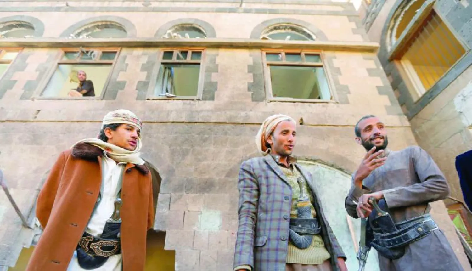 حوثيون يقفون أمام بناية تعرضت لهجوم من مقاتلين منهم في صنعاء بداية الشهر الحالي (رويترز)