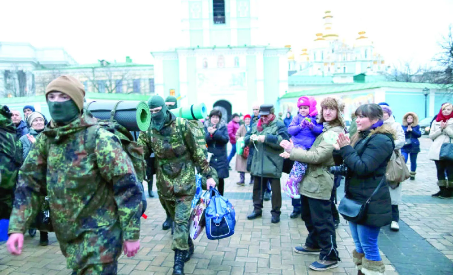 أقارب متطوعين جدد يودعونهم في كييف أثناء توجههم لجبهات القتال في شرق أوكرانيا أمس (رويترز)