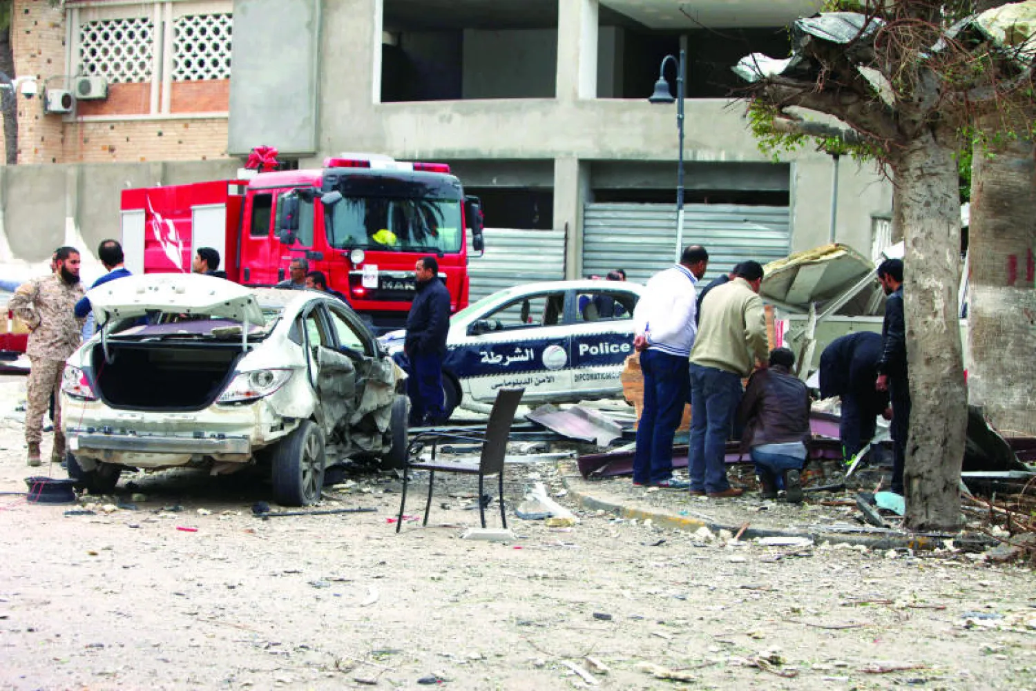 رجال شرطة وإطفائيون ليبيون يعاينون آثار التفجير الذي تعرضت له السفارة الجزائرية في طرابلس أمس (إ.ب.أ)