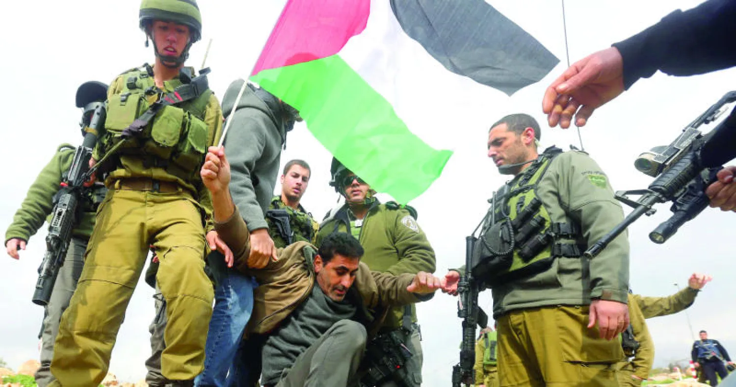 جنود اسرائيليون يعتقلون فلسطينيا حاول إزالة بوابة أقيمت أمام إحدى المستوطنات اليهودية جنوب الضفة أمس (إ. ب. أ)