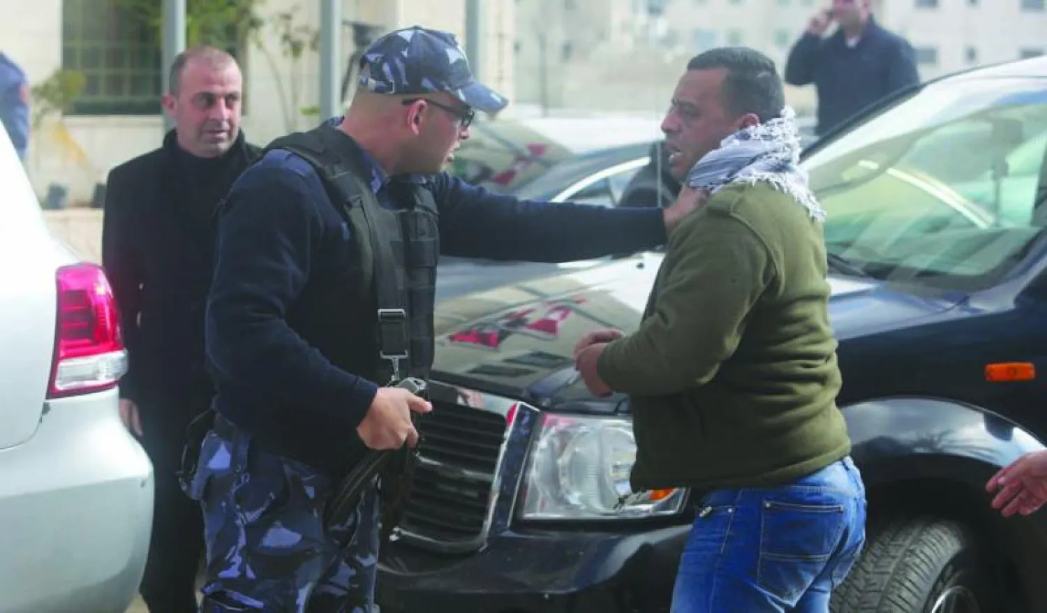 رجل شرطة فلسطيني يواجه أحد المتظاهرين ضد وزير الخارجية الكندي أمام مبنى وزارة الخارجية الفلسطينية في رام الله أمس (أ.ف.ب)