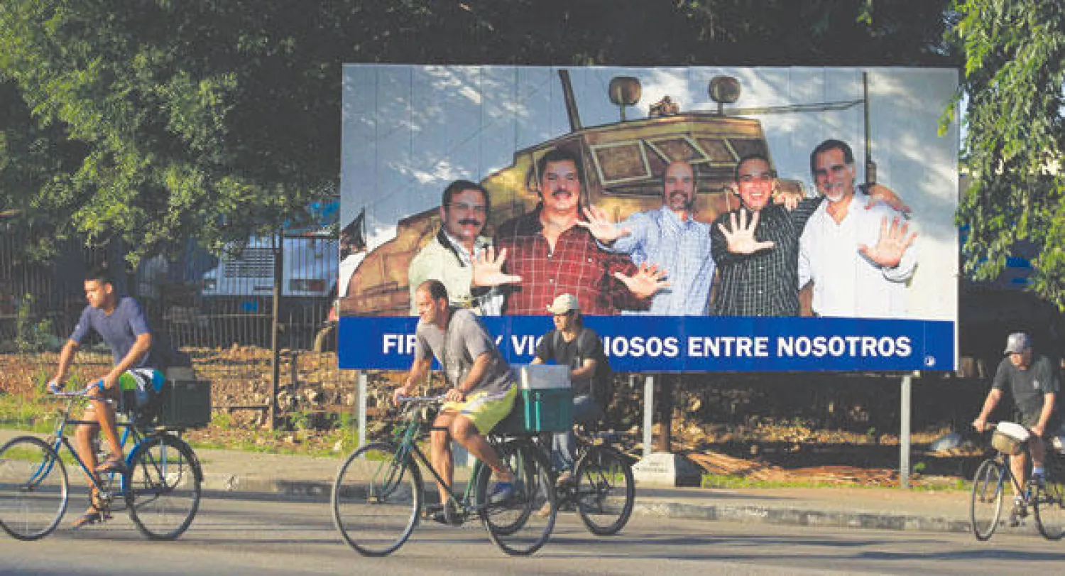 كوبيون يقودون دراجاتهم أمام صورة كبيرة لـ«الكوبيين الخمسة» الذين أفرجت عنهم الولايات المتحدة في أحد شوارع هافانا الأسبوع الماضي (رويترز)