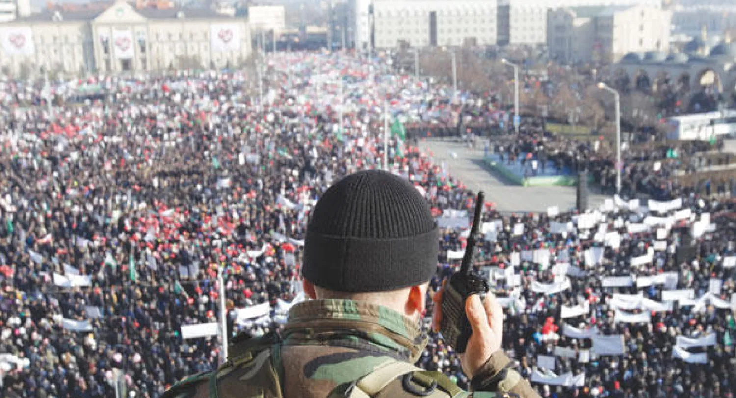 عسكري شيشاني يستخدم جهاز اتصال أثناء مراقبته مسيرة حاشدة ضد الرسوم المسيئة للإسلام في غروزني أمس (رويترز)