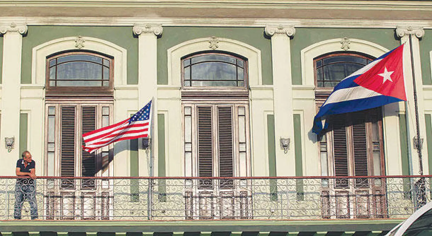 رجل يقف أمام علمي كوبا والولايات المتحدة في شرفة فندق نزل فيه الوفد الأميركي بهافانا أمس عشية بدء المحادثات بين البلدين (رويترز)