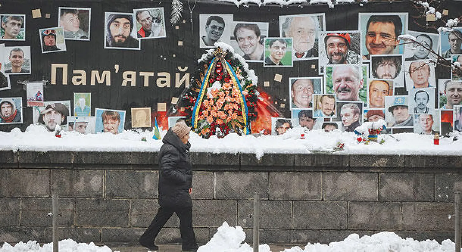 رجل يمر أمس أمام لافتة مكتوب عليها «لنتذكر» وضعت وسط صور بعض من سقطوا خلال احتجاجات «الميدان» بوسط كييف (إ.ب.أ)