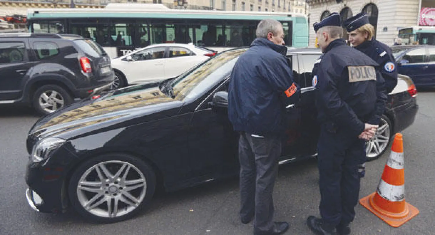 رجال شرطة فرنسيون لدى تفتيشهم إحدى السيارات في إطار الحملة الأمنية في باريس أمس (أ.ف.ب)