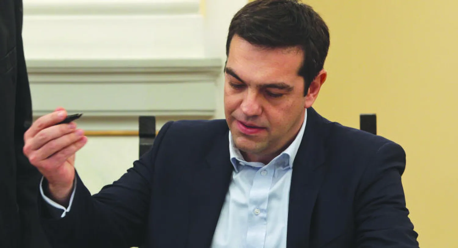 أليكسيس تسيبراس زعيم حزب «سيريزا» يوقع أوراقا رسمية بعد أدائه القسم لتولي رئاسة الحكومة أمس (إ.ب.أ)