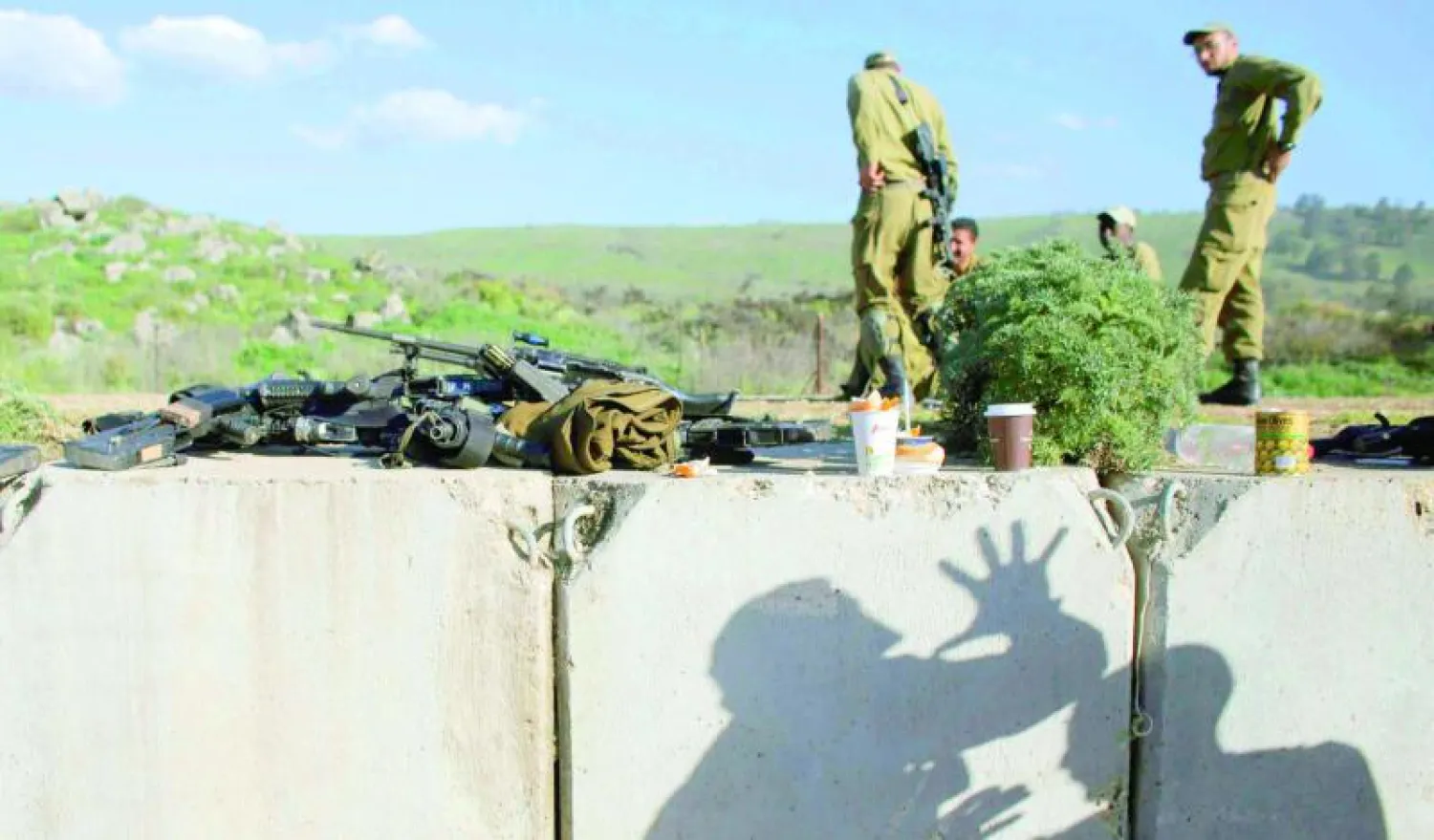 جنود إسرائيليون على جدار في الطرف الإسرائيلي من الحدود مع لبنان حيث بدأت الأمور تعود إلى وضعها الطبيعي (رويترز)