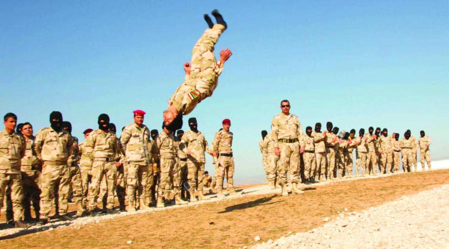 أحد المتطوعين ضمن «الحشد الشعبي» لتحرير الموصل يؤدي قفزة في الهواء خلال التدريبات بمعسكر قرب دهوك (رويترز)