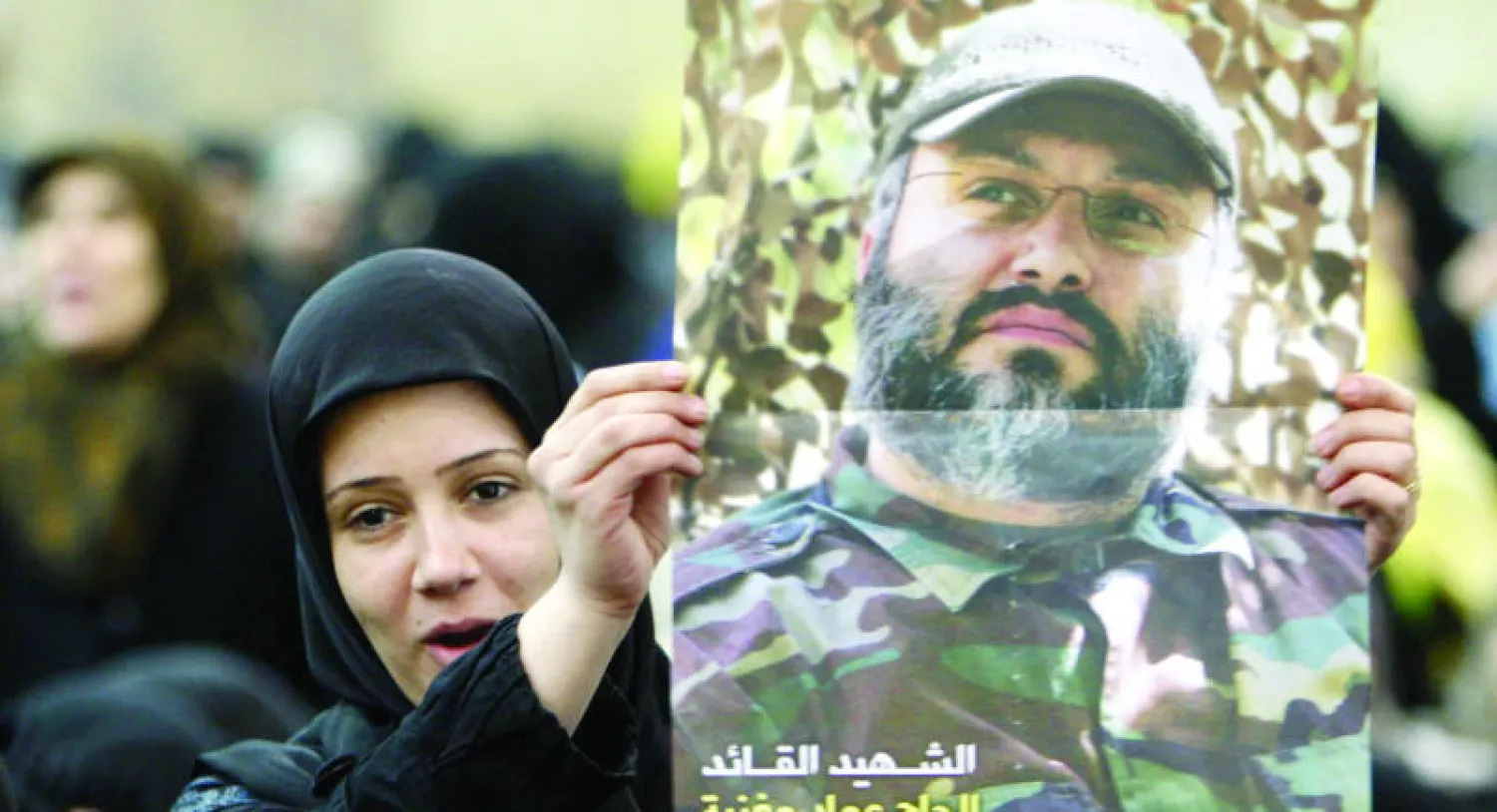 لبنانية تحمل ملصقا لعماد مغنية خلال تجمع حاشد في الضاحية الجنوبية من بيروت يوم 16 فبراير 2009 لإحياء الذكرى السنوية الأولى للقيادي بـ«حزب الله» (أ.ب)