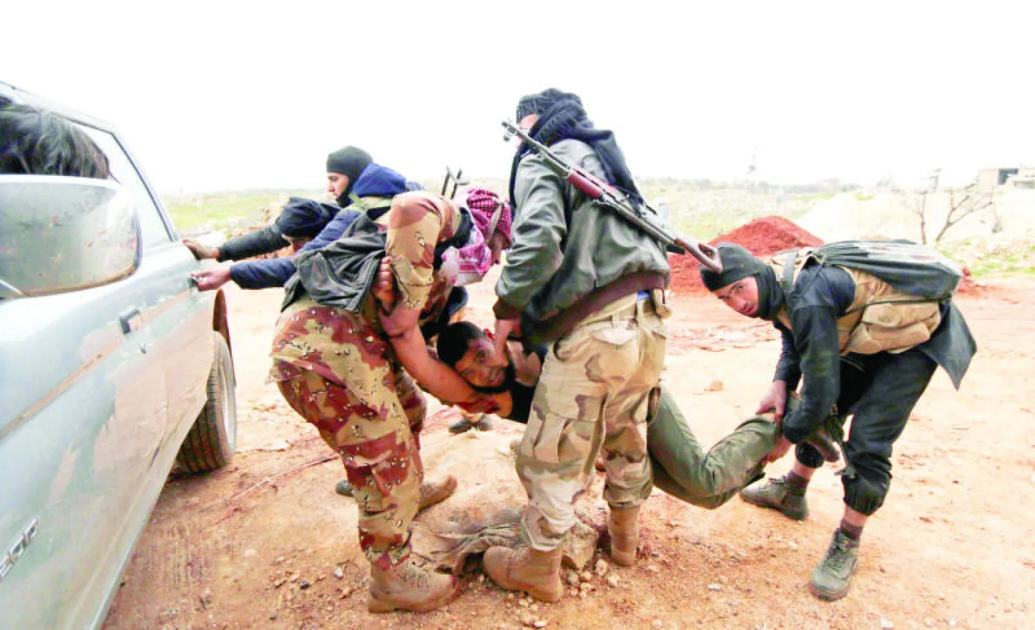 مقاتلون من لواء «صقور الشام» التابع للجيش السوري الحر يحملون أحد جرحى اللواء بعد إصابته في اشتباكات مع قوات النظام في المنطقة الجبلية بغرب إدلب (رويترز)