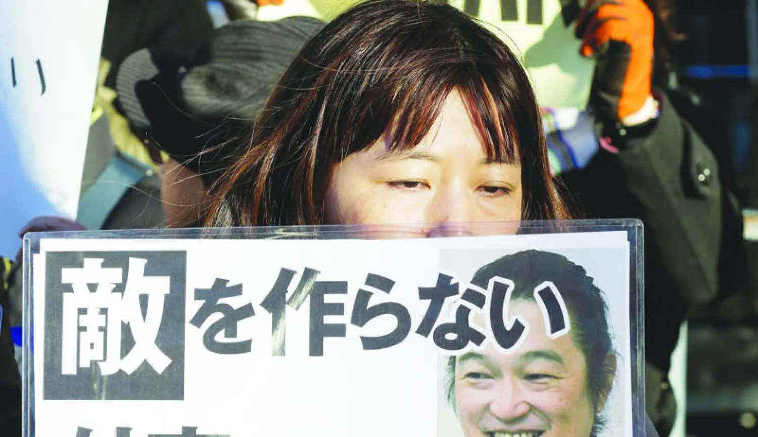 يابانية تحمل صورة الرهينة كينجي غوو الذي أعدمه «داعش» أمس وسط موجة استياء وغضب من قبل المجتمع الدولي (إ.ب.أ)