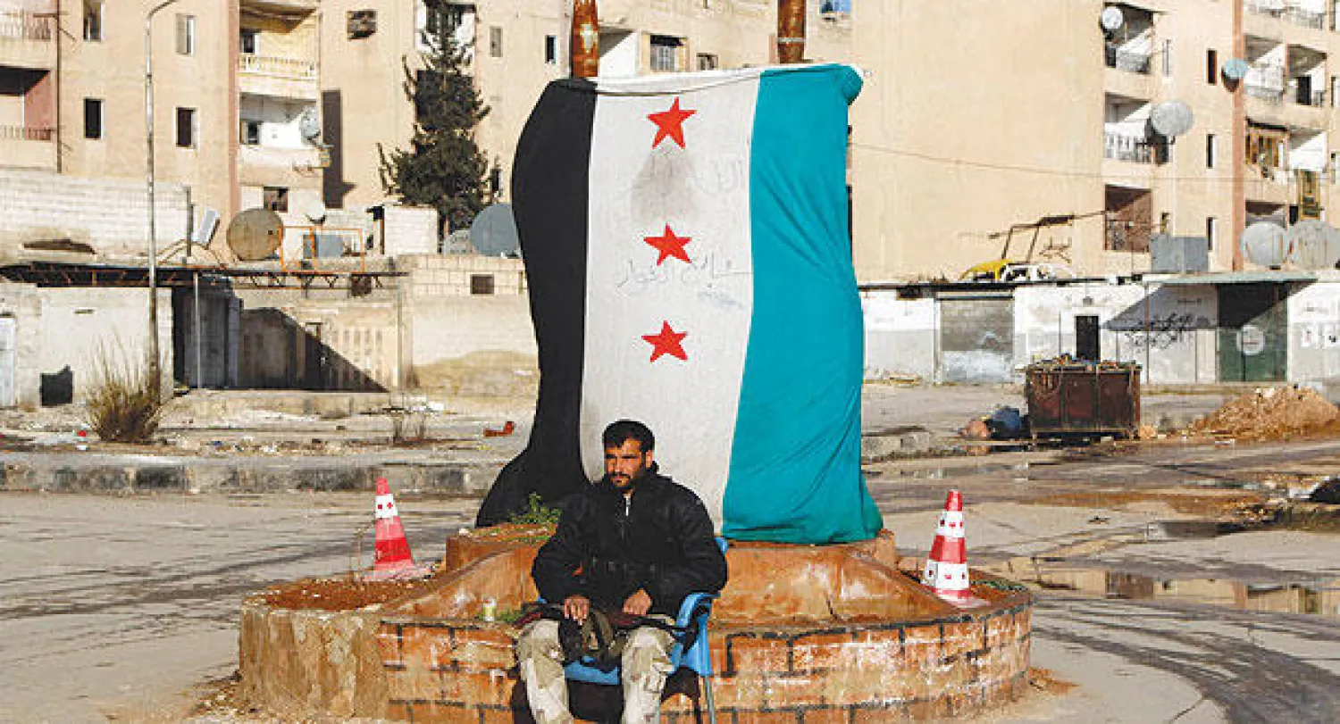 أحد مقاتلي «الجبهة الشامية» التي تشكلت أخيرا في الشمال السوري يجلس عند حاجز تفتيش بمساكن هنانو بحلب (رويترز)