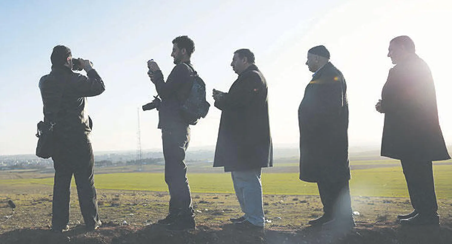 صحافيون وأشخاص آخرون يتابعون دمار مدينة كوباني (عين العرب) من قرية شورش التركية (إ.ب)