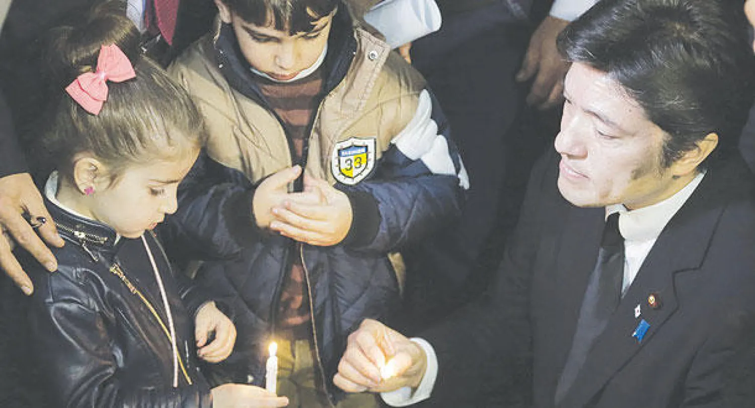 وكيل وزير الخارجية الياباني ياسوهيدا ناكاياما مع طفلين أردنيين في وقفة صامتة أمام سفارة اليابان بعمان أمس تضامنا مع الرهينتين المقتولين اليابانيين والرهينة الأردني معاذ الكساسبة (أ.ف.ب)