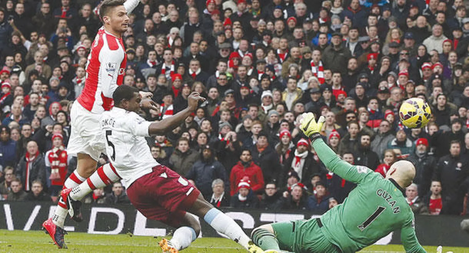 جيرو مهاجم آرسنال (يسار) يسجل من فوق حارس فيلا محرزا ثاني أهدافه من خماسية فريقه (أ.ف.ب)