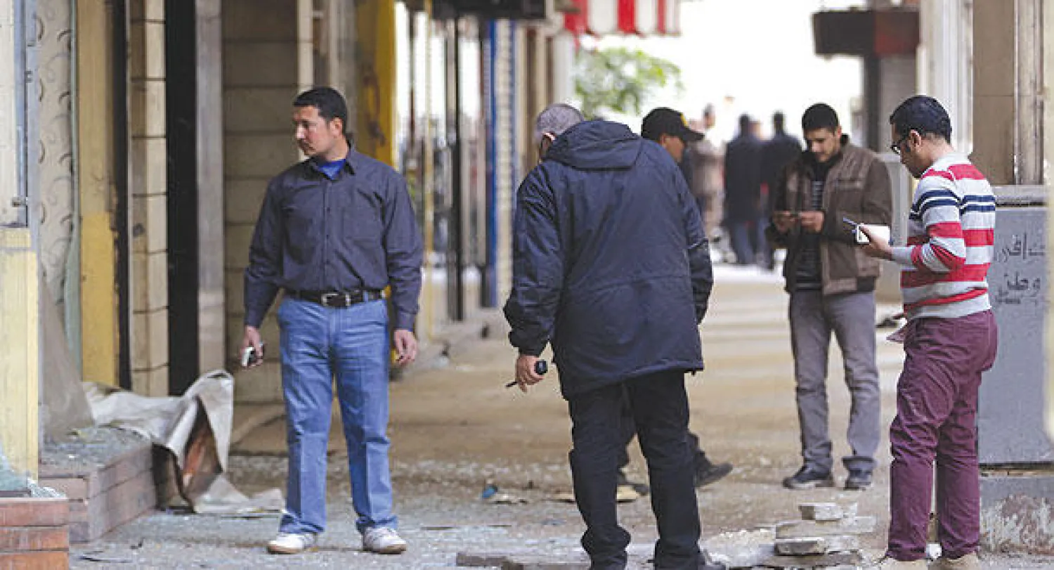 رجال من الشرطة المصرية يفحصون آثار التدمير الذي لحق ببعض المتاجر بعد انفجار عبوة محدودة في أحد شوارع وسط القاهرة، (إ.ب.أ)