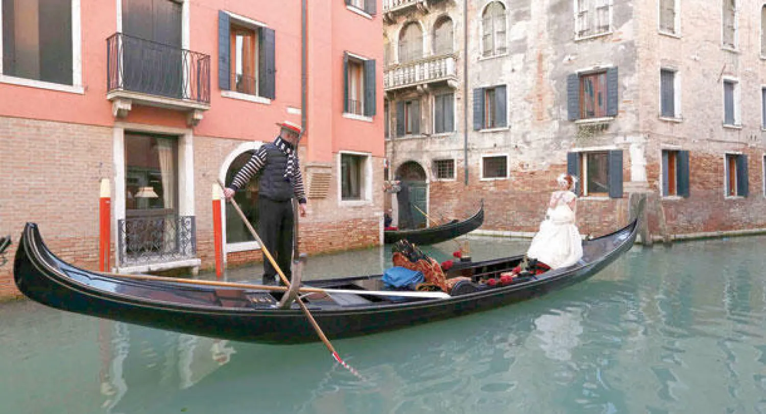 رواد المهرجان بالملابس التاريخية والأقنعة في شوارع وقنوات البندقية (رويترز)