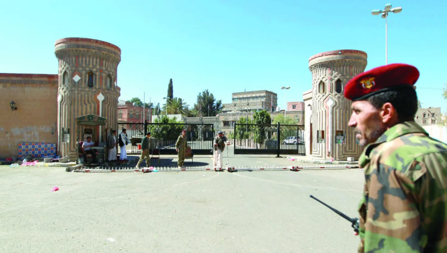 جندي يمني ومسلحون حوثيون يحرسون بوابة القصر الرئاسي في صنعاء أمس (أ.ف.ب)