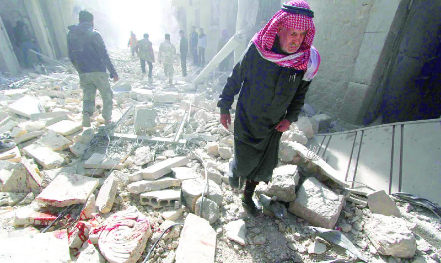 سوريون يمشون وسط الدمار الذي خلفه قصف البراميل المتفجرة من قبل النظام في حلب أمس (رويترز)