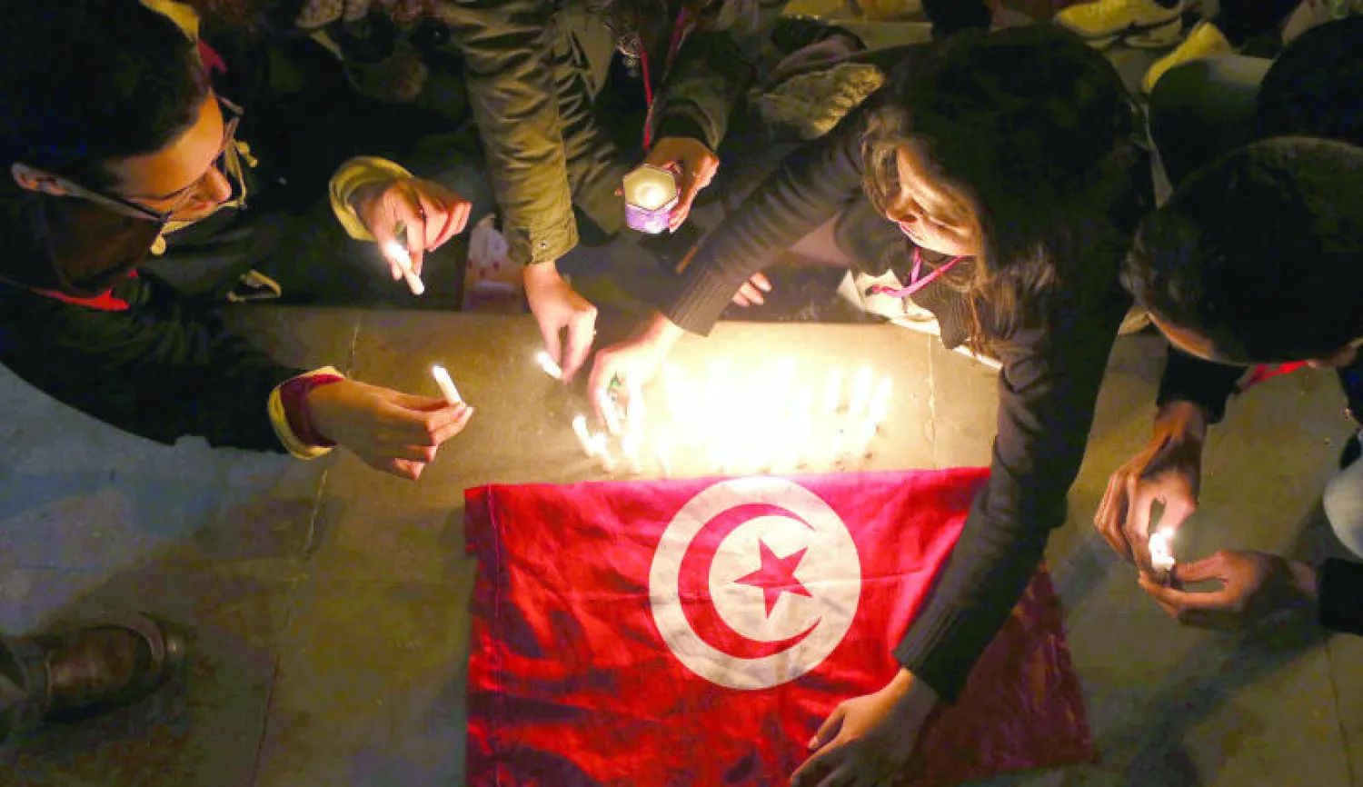 تونسيون يحيون بالشموع الذكرى الثانية لمقتل الناشط والمعارض شكري بلعيد في تونس أول من أمس (إ. ب. أ)