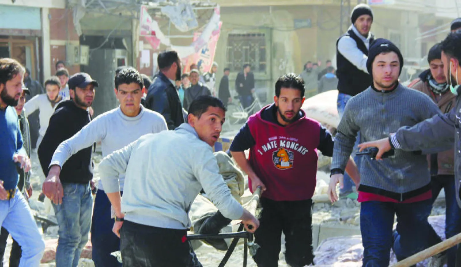 مسعفون من مدينة حمص يحملون المصابين من قصف طيران النظام لأيام حي الوعر بالبراميل المتفجرة (رويترز)