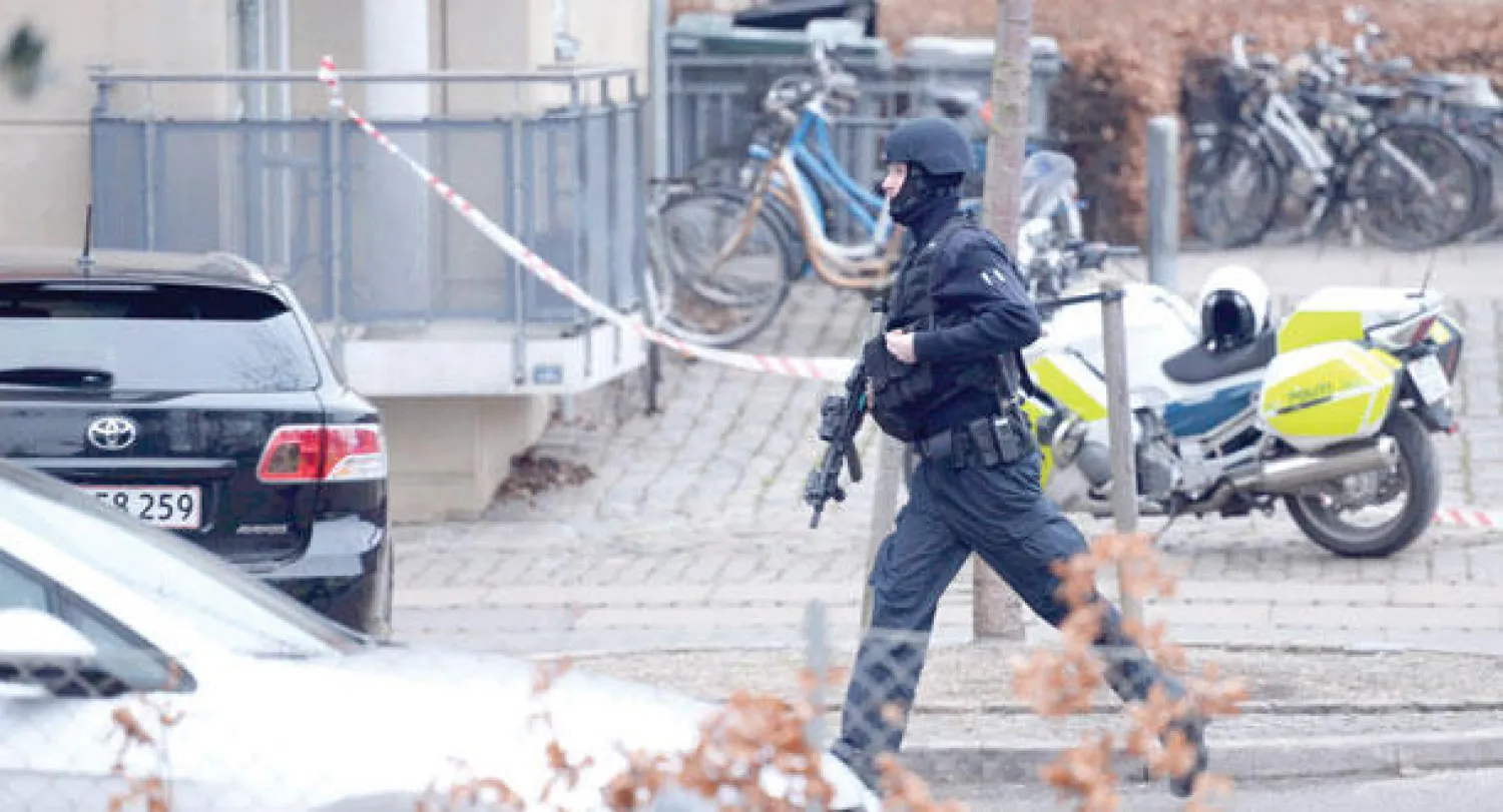 شرطي يسير مسرعا أمام المركز الثقافي الذي شهد الهجوم في كوبنهاغن أمس (أ.ب)