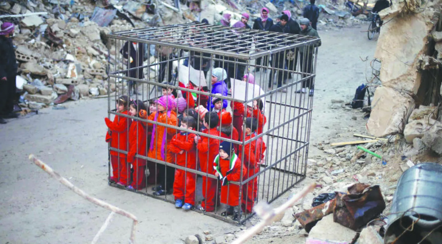 اطفال دوما بقمصان برتقالية، يستلهمون القفص الذي احرقت فيه داعش الطيار الاردني، ويعتصمون احتجاجا على غارات النظام الجوية منذ اسبوعين