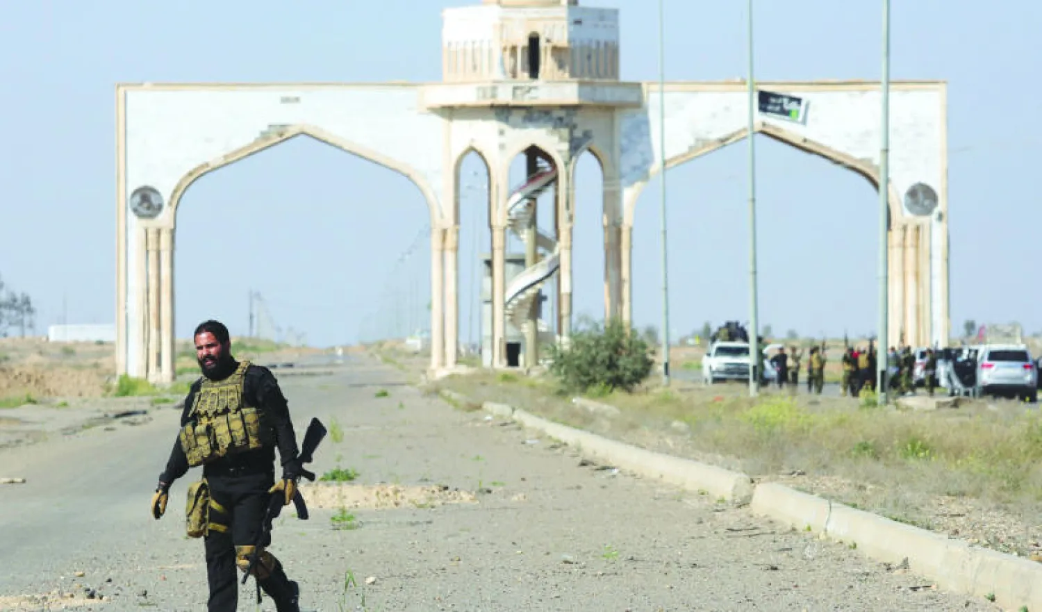 مقاتل من «الحشد الشعبي» مع سلاحه أمام بوابة مدينة تكريت التي دارت معارك في محورها أمس (رويترز)