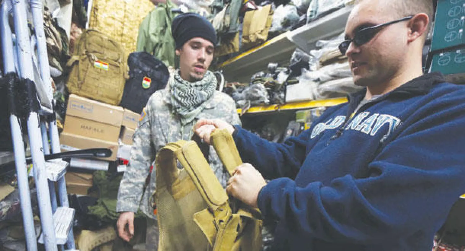 الأميركي لويس بارك ومواطنه (ل) المتطوعان للقتال ضمن مجموعة من المسيحيين العراقيين للقتال ضد «داعش» يعاينان بعض الملابس العسكرية في محل بمدينة دهوك أول من أمس (أ.ف.ب)