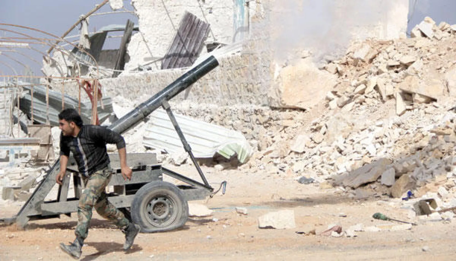 مقاتل سوري لدى فراره بعد أن أطلق نيران مدفعيته باتجاه قوات تابعة للنظام في حلب أمس (أ.ف.ب)