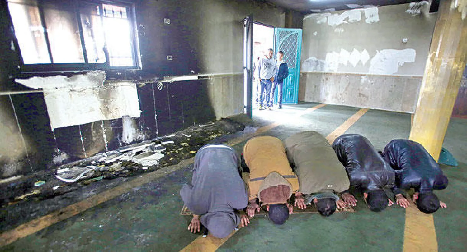 سكان قرية الجبعة في بيت لحم يصلون بمسجد «الهدى» الذي أضرم مستوطنون النيران فيه أمس (إ.ب.أ)